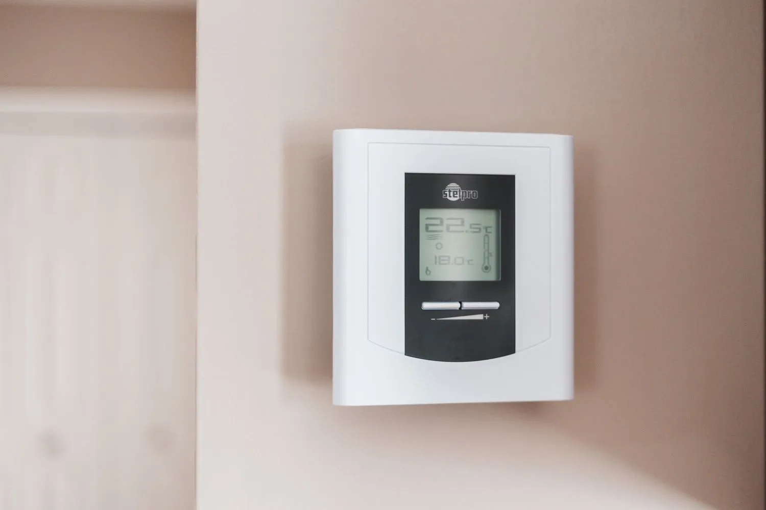 A digital thermostat mounted on a wall